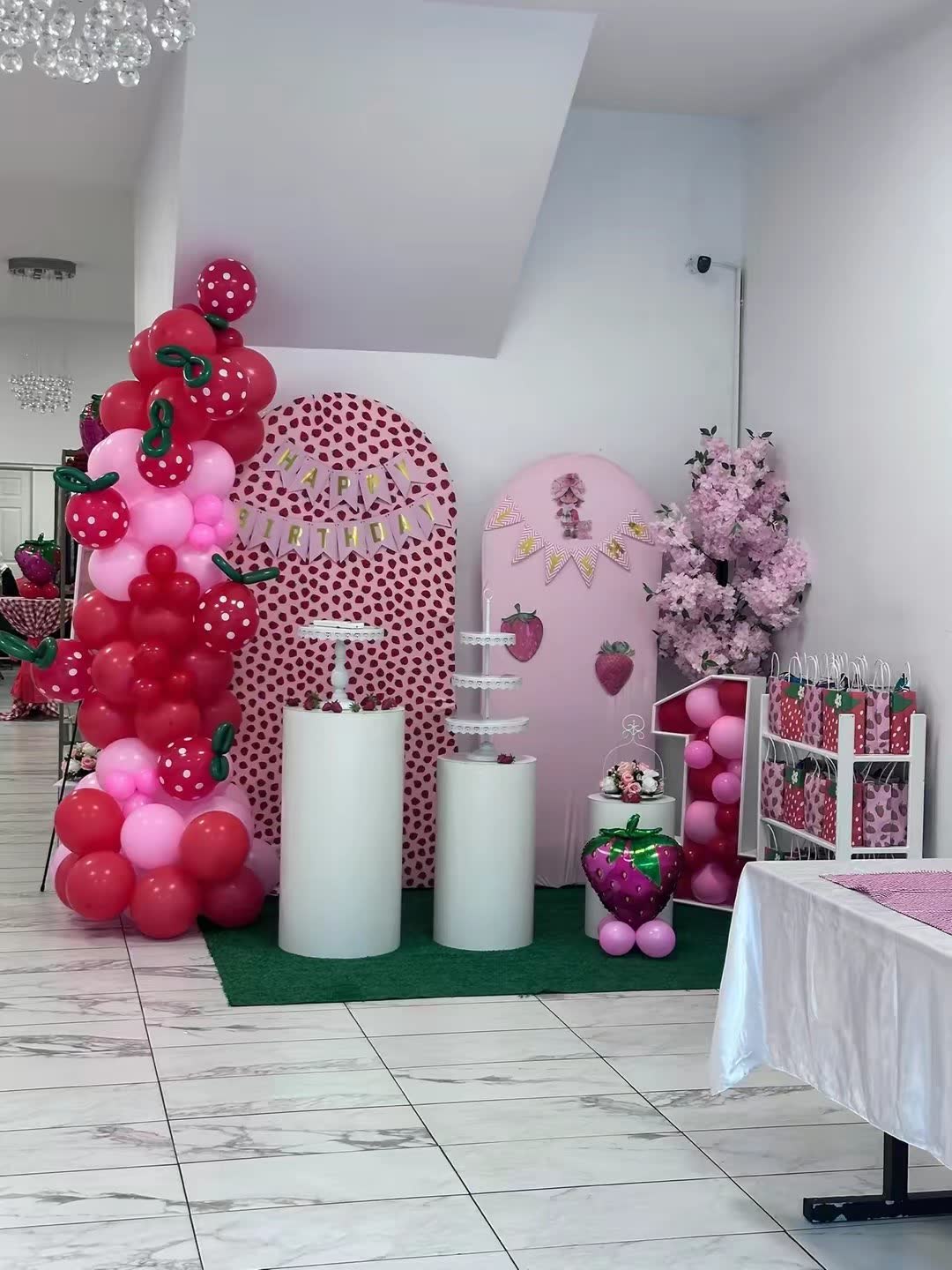 Strawberry first-birthday display with red and pink balloons at Elegance on Varet