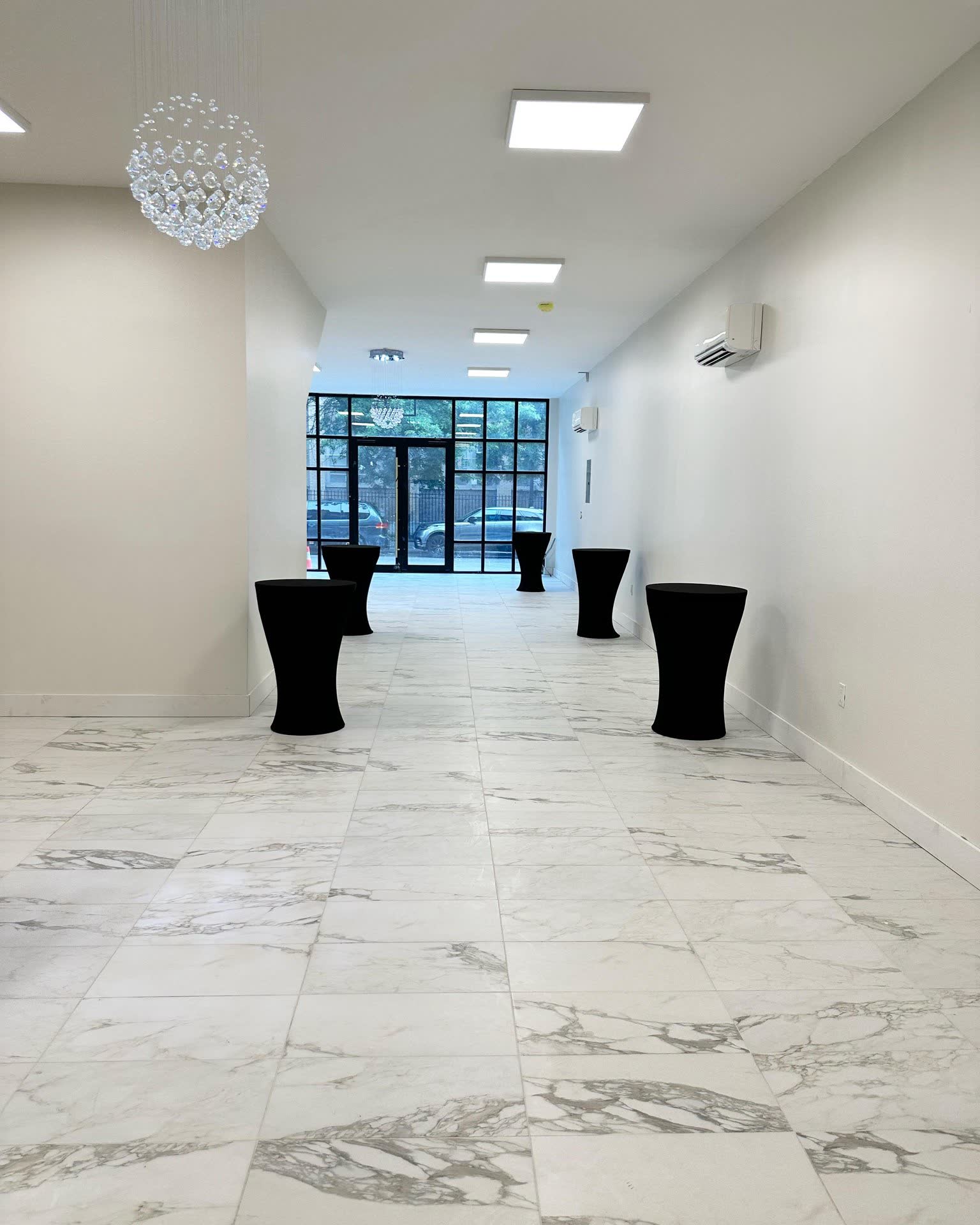 Bright blank-canvas event hall with marble floors and chandeliers at Elegance on Varet